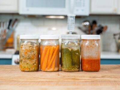 Fyra glasburkar med grönsaker som fermenteras på köksbänken